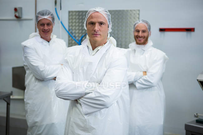 Equipe de açougueiros de pé com os braços cruzados na fábrica de carne — Fotografia de Stock