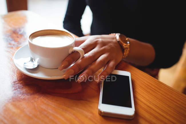A meio da sessão de mulher tomando uma xícara de café no café — Fotografia de Stock