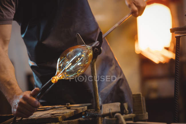 Mid section of glassblower shaping a molten glass at glassblowing factory — Stock Photo