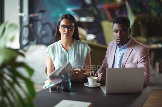 Portrait of businessman and a colleague at desk in office — Stock Photo