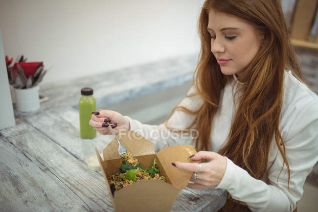 Beautiful woman eating salad in modern restaurant — Stock Photo