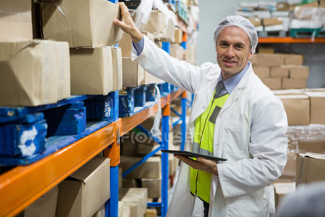 Male technician maintaining record on digital tablet at meat factory — Stock Photo