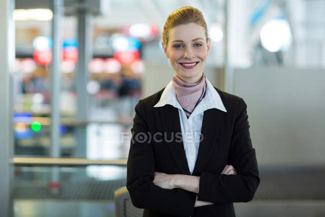 Portrait of smiling airline check-in attendant at counter in airport terminal — Stock Photo
