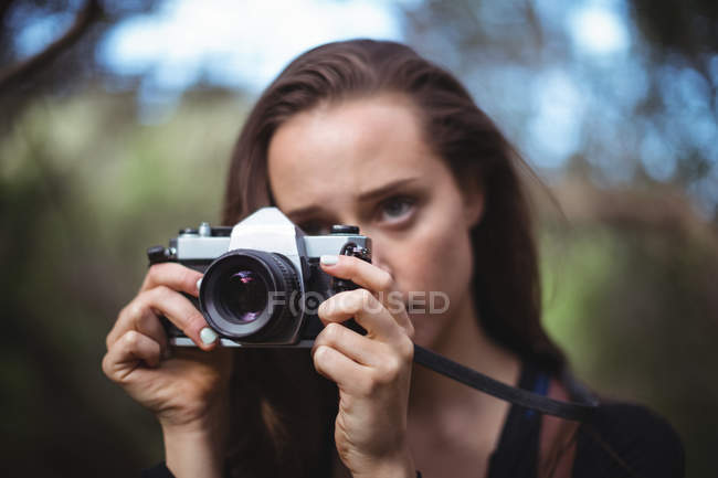 Hermosa mujer de pie con cámara en el bosque - foto de stock