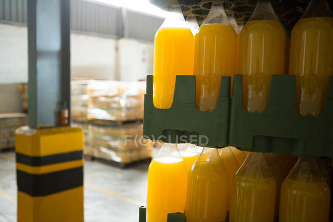Close up de garrafas de suco amarelo dispostos em caixa no armazém — Fotografia de Stock