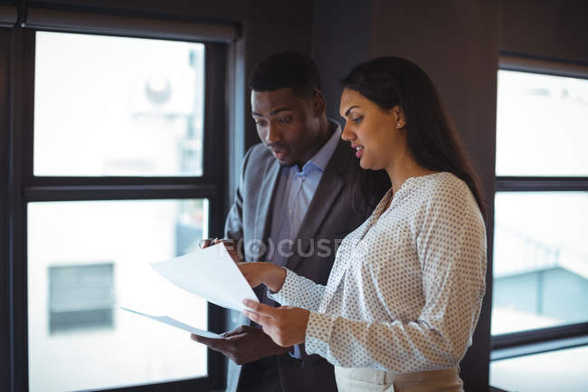 Un homme d'affaires et un collègue discutent d'un document au bureau — Photo de stock