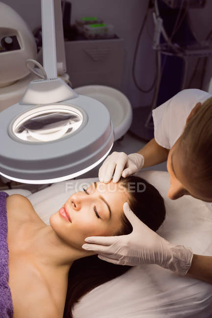 Dermatólogo examinando piel de paciente femenina en clínica - foto de stock