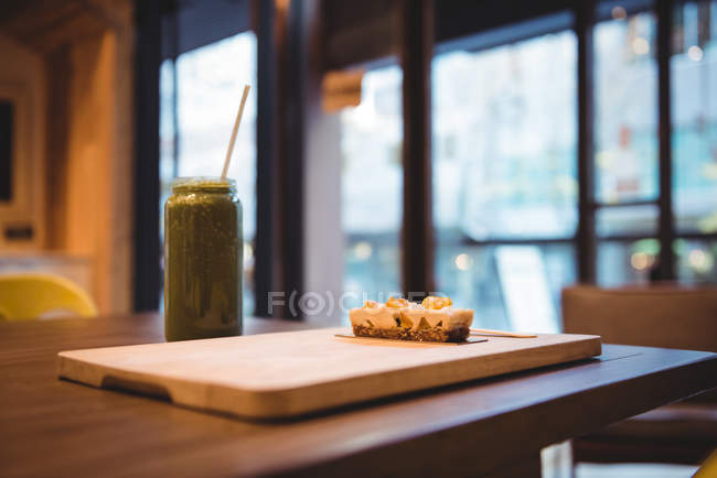 Green smoothie juice and sweet dessert on table in cafe — Stock Photo