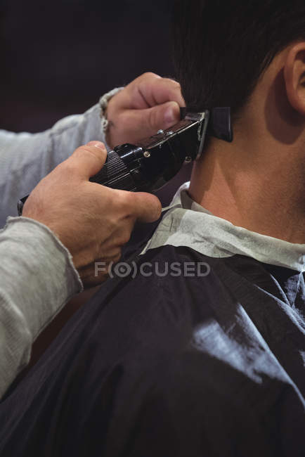Primo piano di uomo ottenere capelli tagliati con trimmer in negozio di barbiere — Foto stock