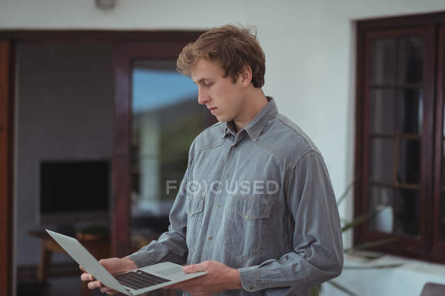 Homme debout à la maison et regardant ordinateur portable — Photo de stock