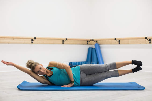 Woman performing stretching exercise in gym — Stock Photo