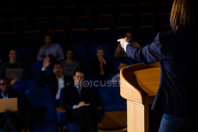 Vue arrière d'une dirigeante d'entreprise qui prononce un discours au centre de conférence — Photo de stock