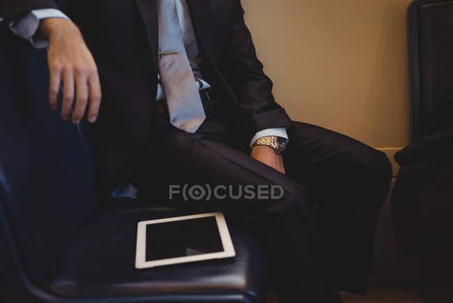 Mid section of businessman with digital tablet travelling in train — Stock Photo