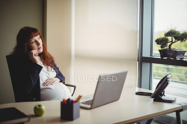 Вагітна бізнес-леді розмовляє по мобільному телефону в офісі — стокове фото
