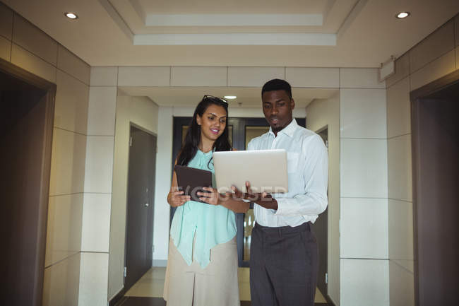 Geschäftsmann und Kollege mit digitalem Tablet und Laptop im Büro — Stockfoto