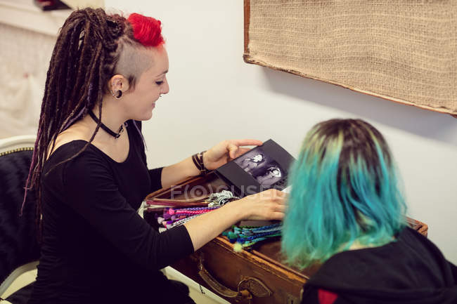 Female shop owner interacting with a customer in dreadlocks shop — Stock Photo