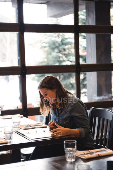Mulher feliz olhando para o menu no restaurante — Fotografia de Stock