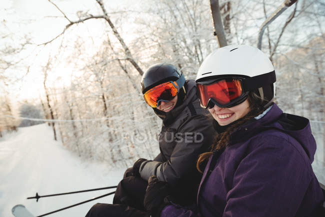 Portrait of happy skier couple sitting at the ski resort — Stock Photo