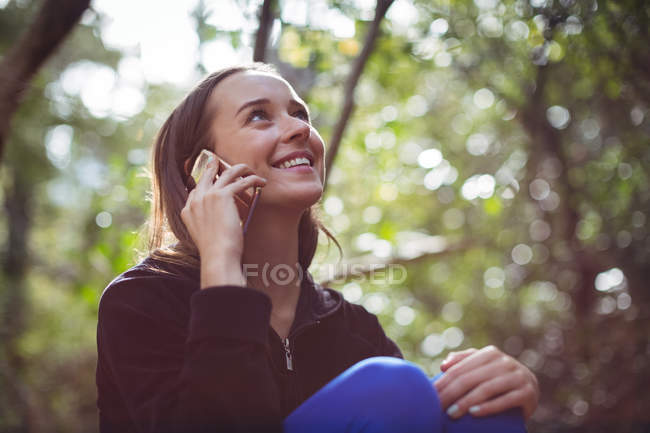 Femme heureuse parlant sur téléphone mobile dans la forêt — Photo de stock
