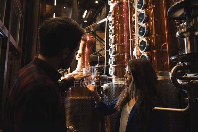 Man and woman examining sample of alcohol in beer factory — Stock Photo