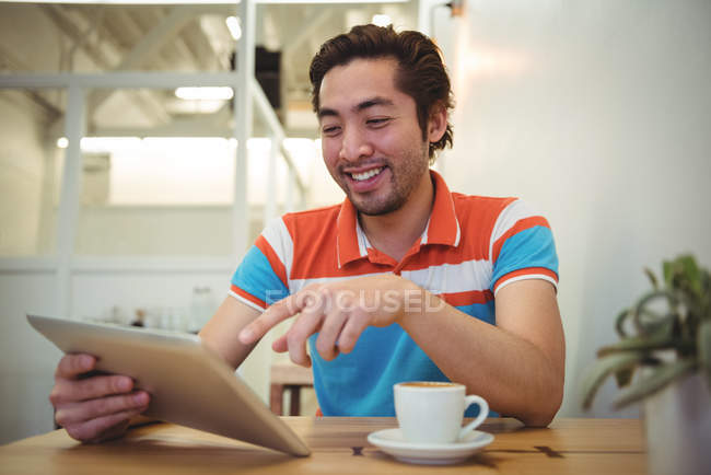 Homme utilisant tablette numérique avec tasse à café sur la table dans un café — Photo de stock