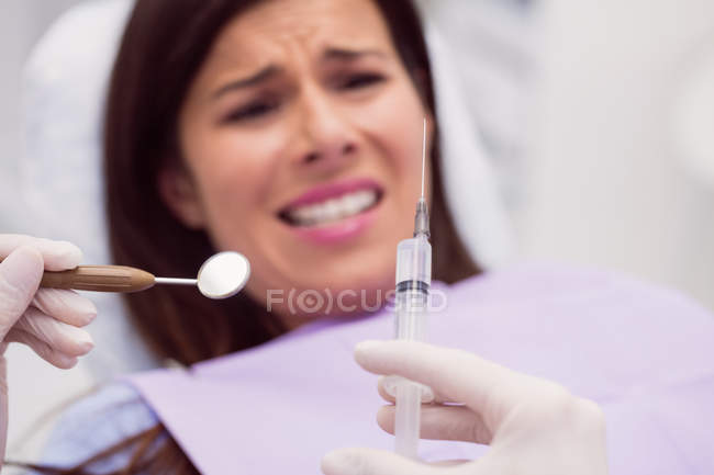 Стоматолог, держащий шприц перед испуганным пациентом в клинике — стоковое фото