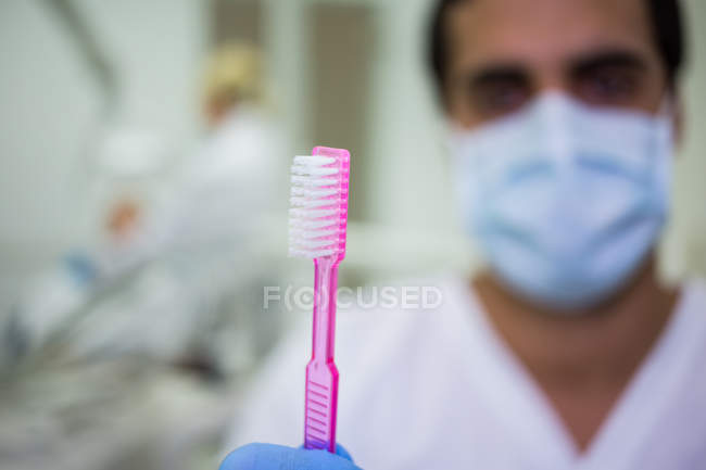 Dentista mostrando escova de dentes na clínica odontológica — Fotografia de Stock
