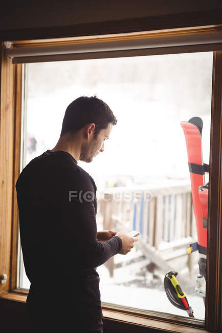 Mann mit Handy vor Fenster eines Skigebiets — Stockfoto