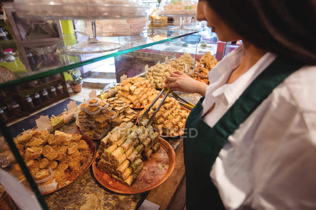 Verkäuferin arrangiert türkische Süßigkeiten an der Theke im Geschäft — Stockfoto