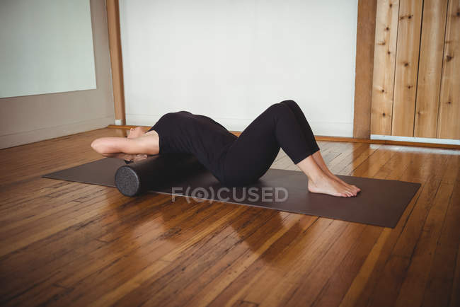 Woman exercising with foam roll in fitness studio — Stock Photo