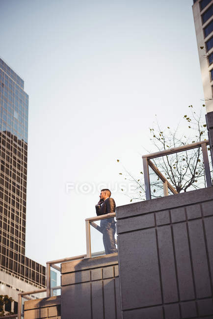 Businessman talking on mobile phone near office building — Stock Photo