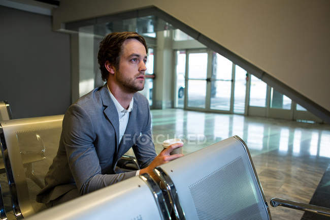 Nachdenklicher Geschäftsmann sitzt im Wartebereich am Flughafen — Stockfoto