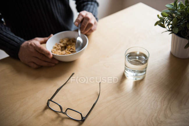 Sección media del hombre desayunando en la sala de estar en casa - foto de stock