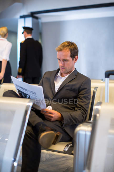 Empresário lendo jornal na área de espera no terminal do aeroporto — Fotografia de Stock
