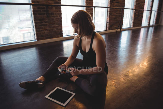 Ballerino seduto sul pavimento e utilizzando il telefono cellulare in studio di danza — Foto stock