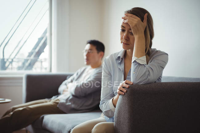 Засмучений пара, сидячи на дивані і ігноруючи один одного — стокове фото