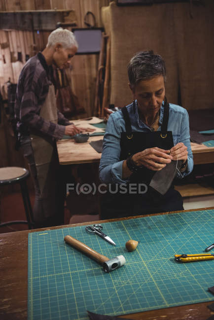 Artesanas trabajando en una pieza de cuero en taller - foto de stock