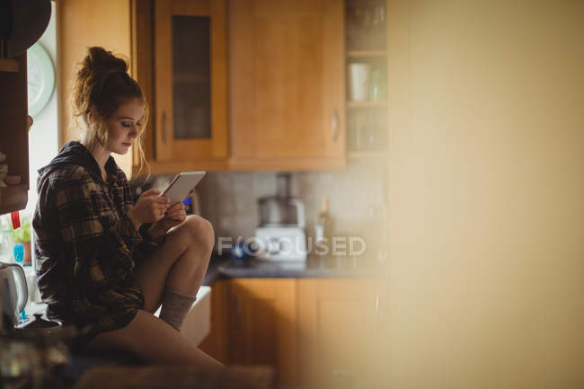 Beautiful woman using digital tablet in kitchen at home — Stock Photo