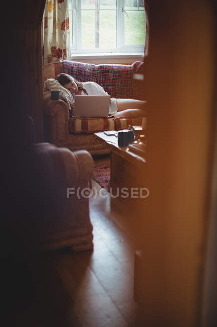 Schöne Frau auf Sofa liegend und mit Laptop im Wohnzimmer zu Hause — Stockfoto
