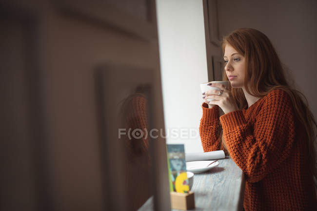 Ruiva mulher tomando café na janela do restaurante — Fotografia de Stock