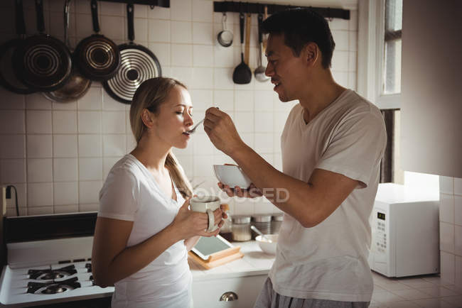 Мужчина кормит женщину на кухне дома — стоковое фото