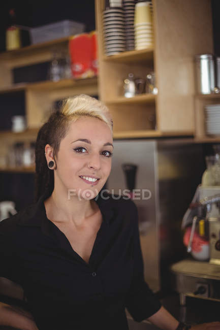 Портрет усміхненої офіціантки, що стоїть руками на стегнах у кафе — стокове фото