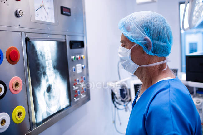 Chirurgo maschio che legge radiografie in sala operatoria — Foto stock