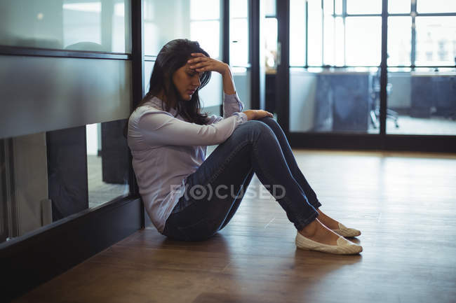 Femme d'affaires bouleversée assise sur le sol dans le bureau — Photo de stock