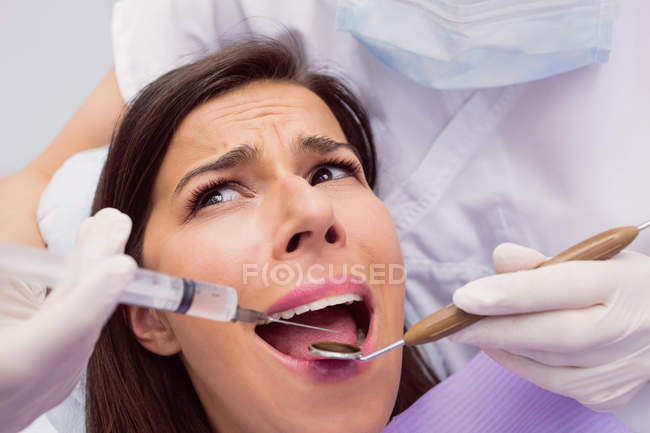 Dentista iniettando anestetici in bocca paziente femminile spaventato in clinica — Foto stock