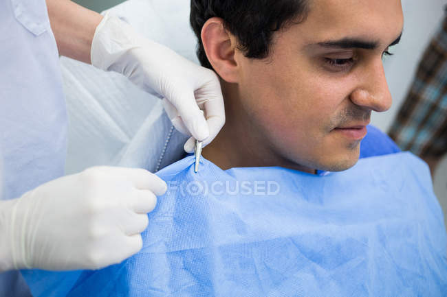 Dentista che assiste il paziente a indossare grembiule dentale presso la clinica — Foto stock