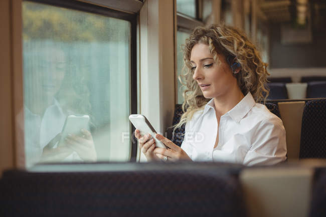 Blonde Geschäftsfrau nutzt Smartphone während Zugfahrt — Stockfoto