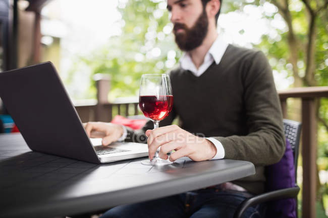 Человек с ноутбуком во время бокала вина в баре — стоковое фото