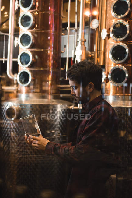 Man examining sample of alcohol in beer factory — Stock Photo