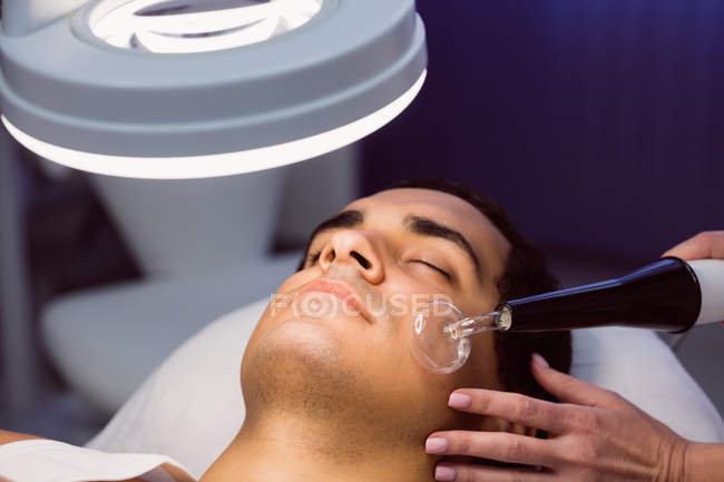 Hombre recibiendo masaje facial para tratamiento cosmético en la clínica - foto de stock